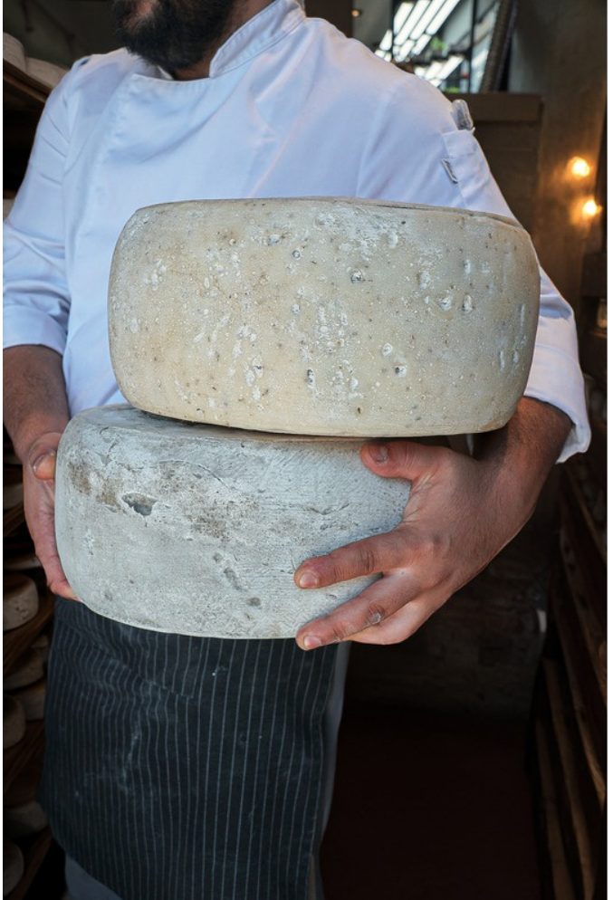 Cheesemaker holding two Ariste wheels